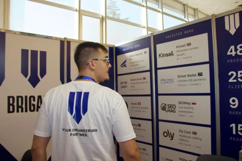 A Brigada team member in a Your engineering partner shirt looking at the selected work wall, which lists Kinsail, Street Wallet, SEOMag and Oly Care.